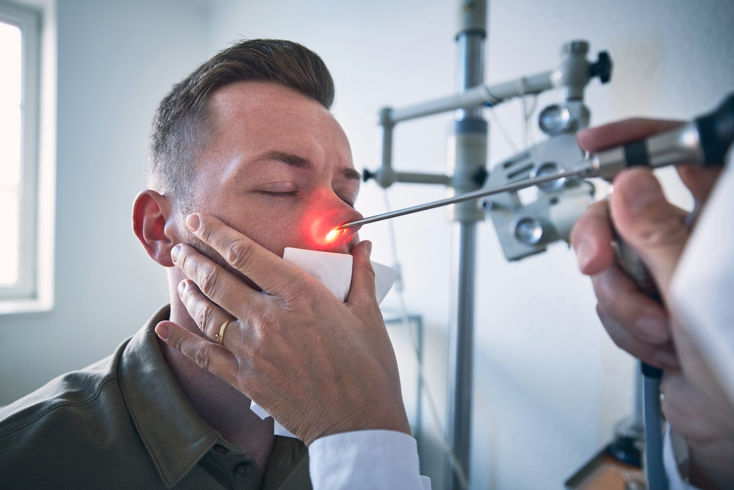 dottore esamina il naso del paziente per vedere se è rotto