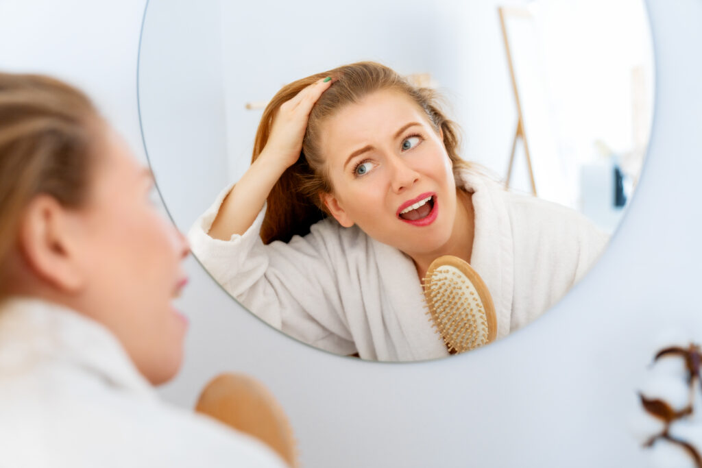 Donna che si guarda l'attaccatura dei capelli allo specchio