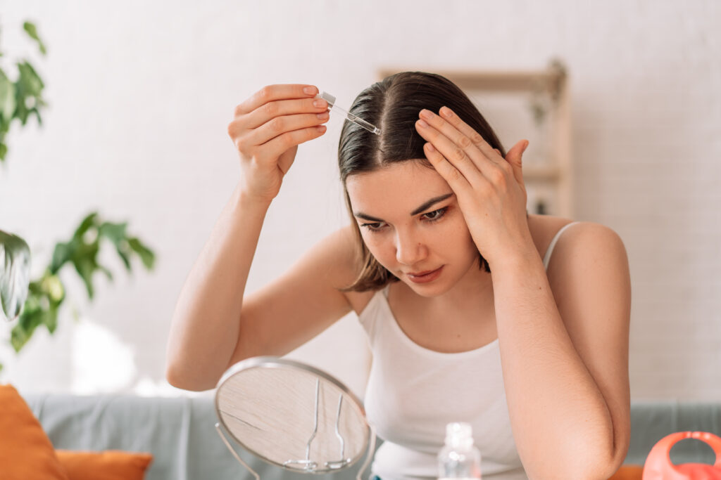 donna applica olio di rosmarino sui capelli